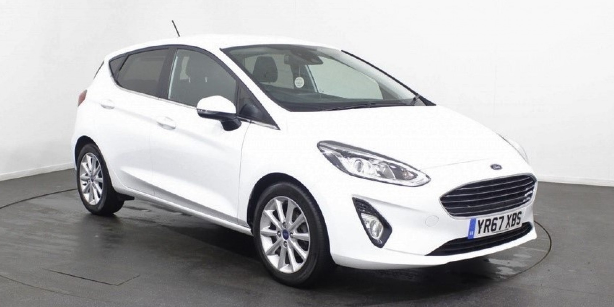 White Ford Fiesta parked in showroom, facing three-quarters right 